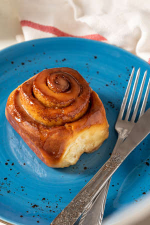 Freshly baked cinnamon roll on a blue porcelain plateの写真素材
