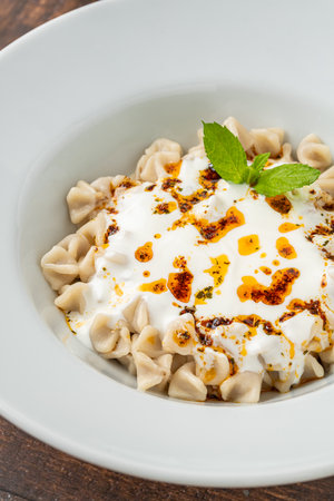 Kayseri ravioli or Kayseri Mantisi on a white plate on wooden tableの写真素材