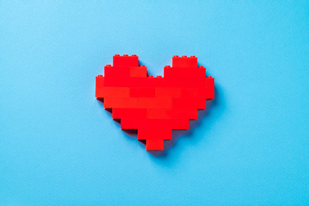 Red heart made of plastic bricks on a blue backgroundの写真素材