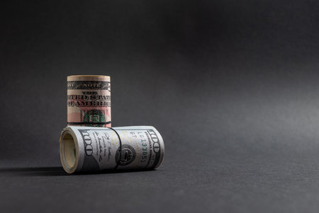 Rolls of 50 and 100 us dollar standing on dark backgroundの写真素材