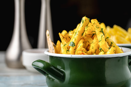 Golden French Fries in an enamel bowl with various sauces on the side