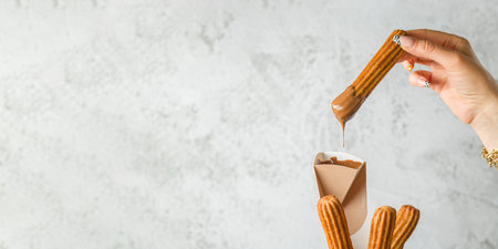 Woman taking churros from a cone and dipping it in chocolate sauce