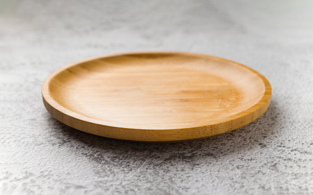 Wooden plate on a white stone background. handmade cooking utensilsの写真素材