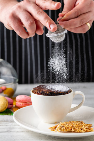 Chocolate soufflÃ© in white porcelain cup on wooden tableの写真素材