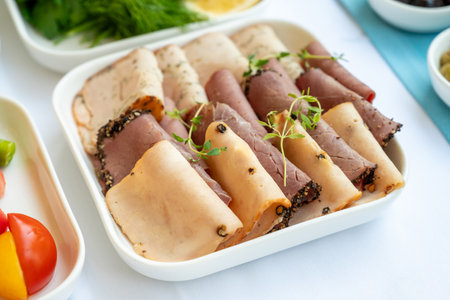 Ham and chicken ham with pepper on white porcelain plate at breakfast table