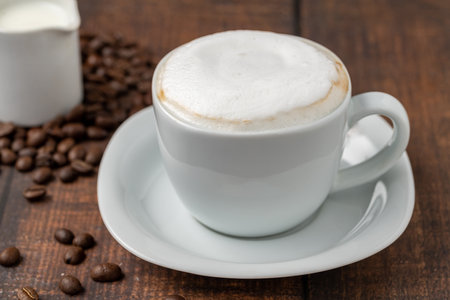 Cappuccino coffee in a white porcelain cup on a wooden tableの写真素材
