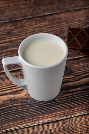 Milk with chocolate in black cup on wooden tableの写真素材