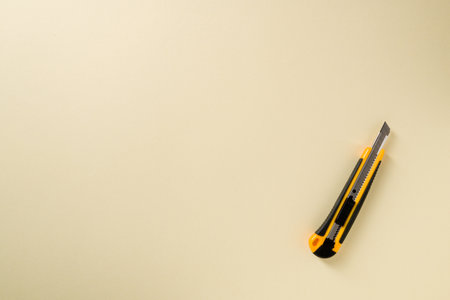 Utility knife with yellow and black handle on a yellow background