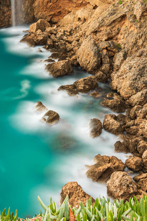 Long exposure photo of waves hitting the rocks of the cliffの写真素材