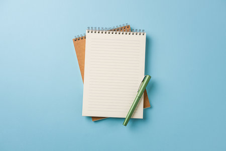 Top view of notebook and fountain pen on blue background