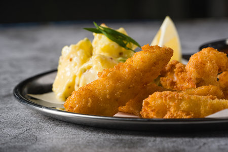 Deep fried shrimp tempura with potato salad on a metal plateの写真素材