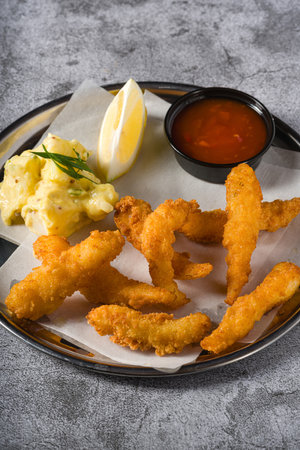 Deep fried shrimp tempura with potato salad on a metal plateの写真素材
