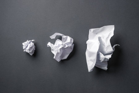 Very, medium and slightly crumpled paper balls on dark gray backgroundの写真素材