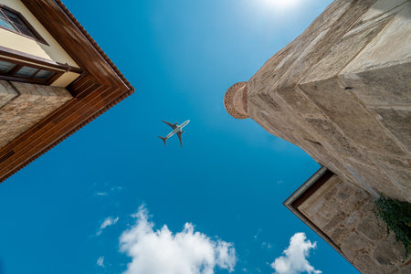 Passenger plane flying over the historical house and truncated minaret in Antalya old town (Kaleici)の写真素材