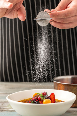 Creme brulee decorated with fruits and powdered sugar on a wooden tableの写真素材