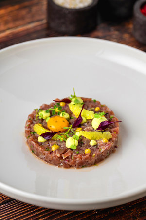 Meat tartare with quail eggs on a white porcelain plateの写真素材