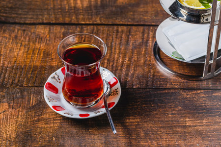 Freshly brewed black Turkish tea with sweetener and lemon slice on wooden tableの写真素材