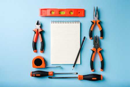 Handled tools or construction tools on blue background with blank notepad and pen in the middleの写真素材