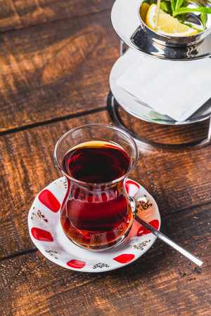 Freshly brewed black Turkish tea with sweetener and lemon slice on wooden tableの写真素材