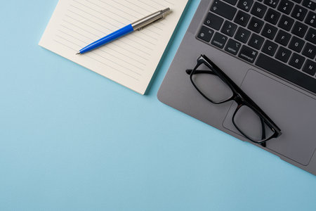 Top view of blue office desk with laptop and supplies. Flat lay business conceptの写真素材