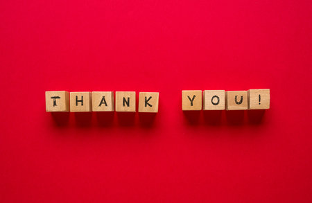 Thank you is written on wooden blocks standing on a red backgroundの写真素材