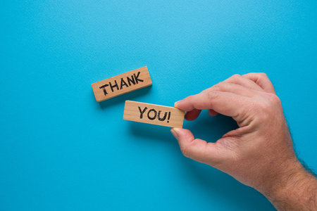 Thank you is written on wooden blocks standing on a blue backgroundの写真素材