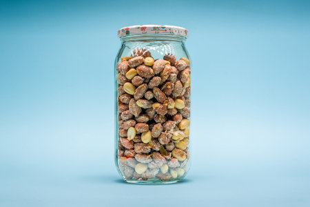 Salted peanuts filled in glass jar on blue backgroundの写真素材
