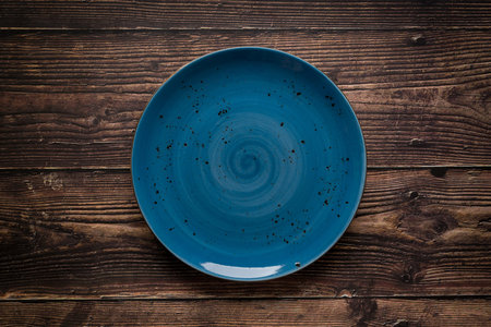 Top view of empty ceramic blue plate on wooden backgroundの写真素材