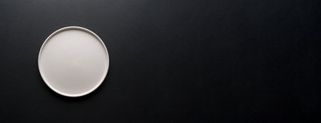 Top view of empty ceramic white plate on black backgroundの写真素材