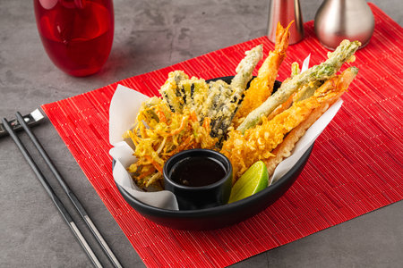 Shrimp tempura with vegetable tempura on a black ceramic plateの写真素材