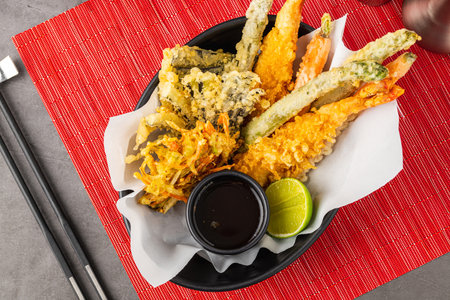 Shrimp tempura with vegetable tempura on a black ceramic plateの写真素材