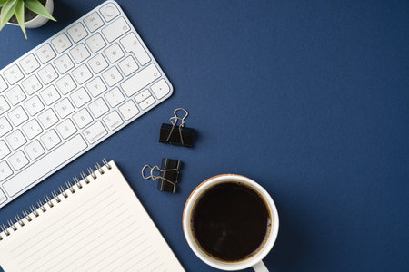 Workspace with keyboard, office supplies, pen and coffee cup. Flat lay, top view blue office desk