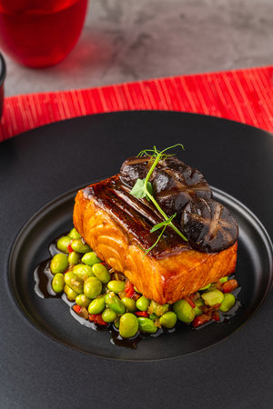 Grilled salmon fillet with edamame and shiitake mushrooms, elegantly served on a black plateの写真素材