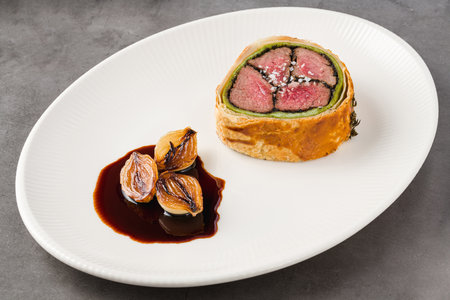 Modern plate of Beef Wellington, caramelized shallots and dark sauceの写真素材