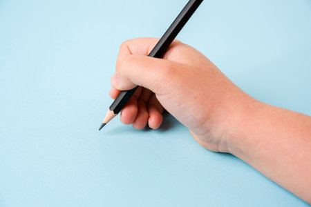 Girl holding pencil with right hand on blue background