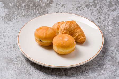 Mini berliner or German donuts and croissant on white plate on stone tableの写真素材