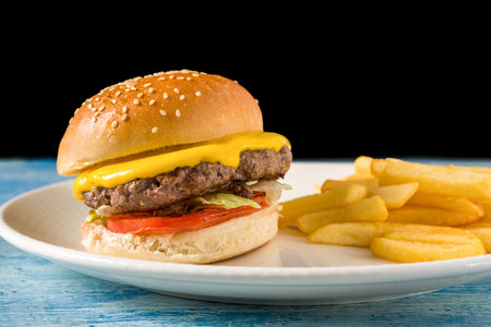 Smash burger with cheddar cheese and caramelized onions, served with friesの写真素材