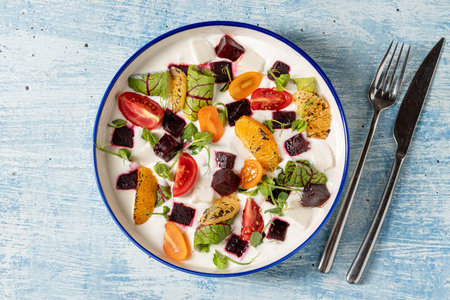 Colorful yogurt salad with grilled oranges, beets, cherry tomatoes, and greensの写真素材