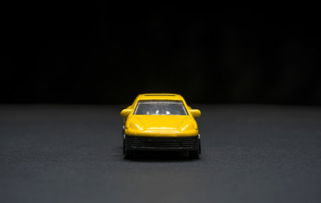 Front view of yellow toy car with sharp details and dark backdropの写真素材