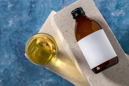 Mockup of amber glass bottle and cocktail on concrete surface