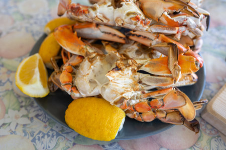 Freshly steamed blue crabs served with lemon wedges on a tableの写真素材