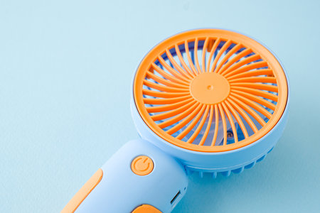 Portable mini hand fan isolated on blue backgroundの写真素材