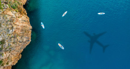 Airplane shadow above boats and rocky coastline aerialの写真素材