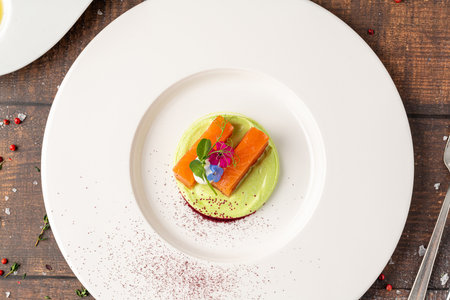 Gourmet salmon fillet with green puree and edible flowers