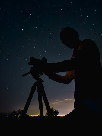 Silhouette of a photographer shooting stars at night under clear skyの写真素材