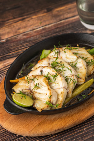 Grilled sea bass fillet served on skillet with vegetablesの写真素材