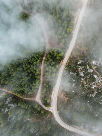Drone view of a winding mountain road cutting through mistの写真素材