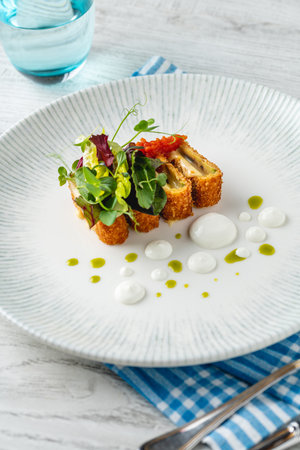 Crispy fish roulade with greens and white sauce dropsの写真素材