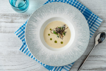 Creamy fish soup served in a blue rimmed bowl with garnishの写真素材