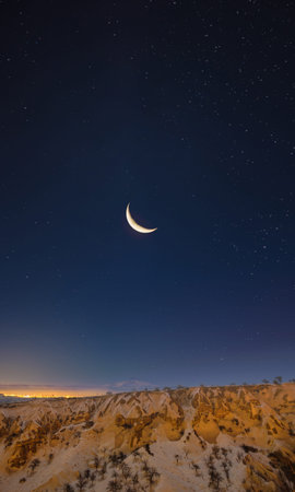 Crescent moon above rocky Cappadocia valley under stars